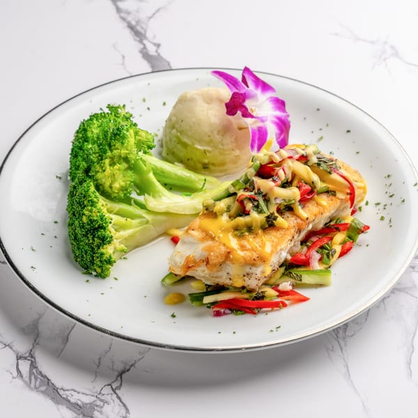Italian fish dish with broccoli, mashed potatoes, and colorful vegetables on a white plate.
