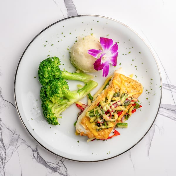 The Bistro K's Italian fish dish with broccoli, mashed potatoes, and a purple orchid garnish.