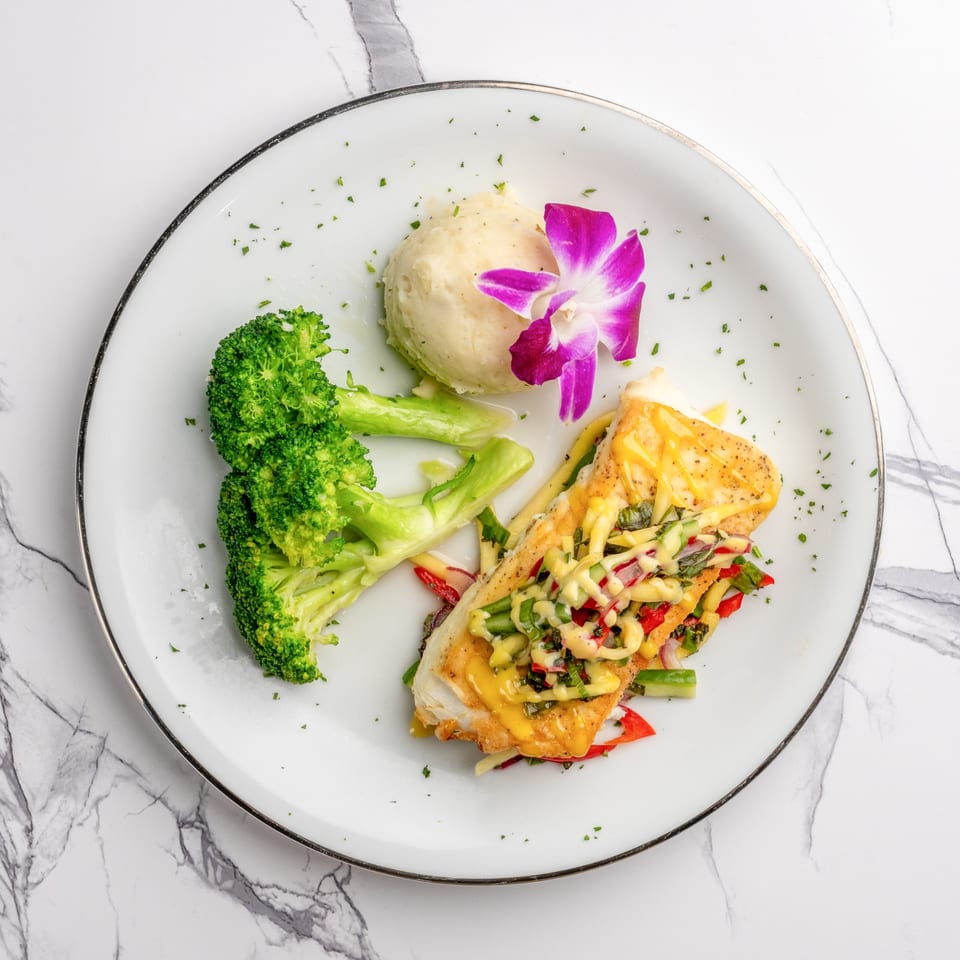 The Bistro K's Italian fish dish with broccoli, mashed potatoes, and a purple orchid garnish.