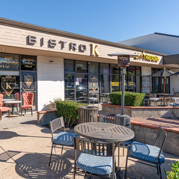 The Bistro K restaurant exterior with outdoor seating, umbrellas, and a patio heater on a sunny day.