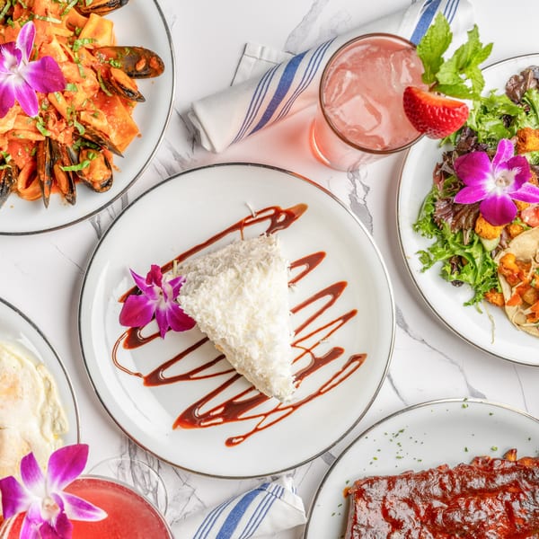 Overhead view of various Italian dishes, including pasta with mussels, ribs, tacos, salad, and dessert.