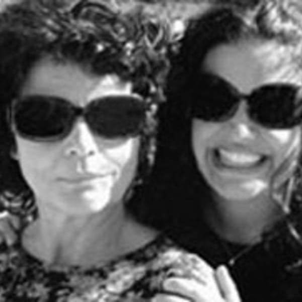 Two women, one smiling broadly, wearing sunglasses in a black and white close-up.