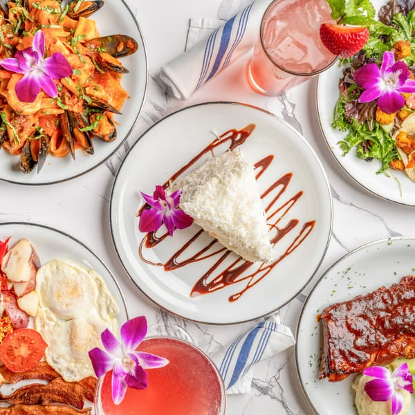 An overhead shot of five plates of Italian dishes, including seafood pasta, ribs, and dessert.