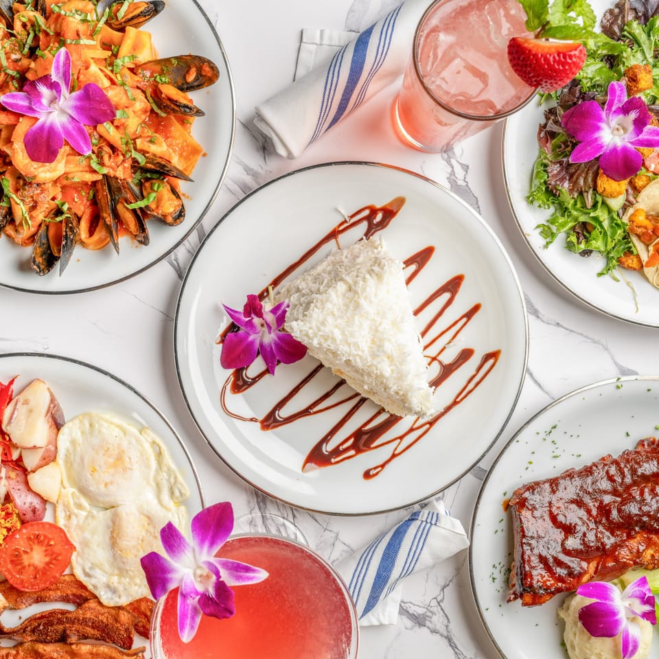 An overhead shot of five plates of Italian dishes, including seafood pasta, ribs, and dessert.