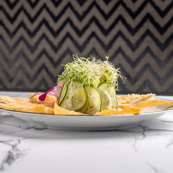 Cucumber and sprout salad with crispy wonton strips and a purple orchid garnish.