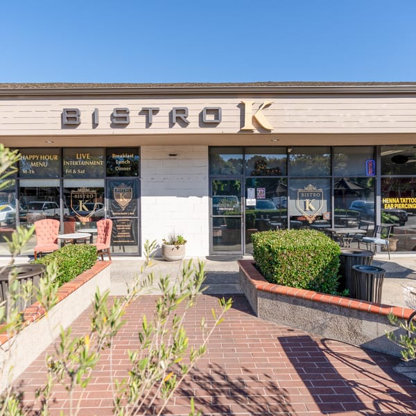 Exterior of The Bistro K, an Italian restaurant, with outdoor seating and a brick walkway.