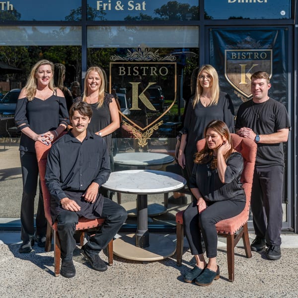 Six Bistro K staff members, dressed in black, pose outside the Italian restaurant.