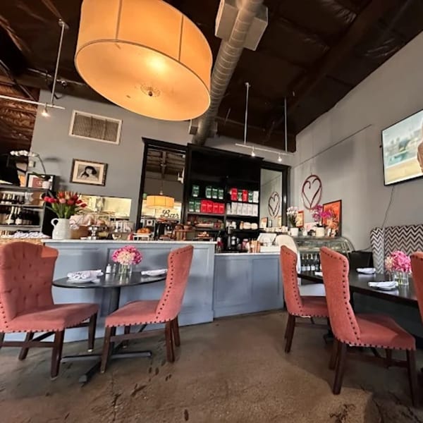The Bistro K's dining area with pink chairs, dark tables, a bar, and a large overhead light.