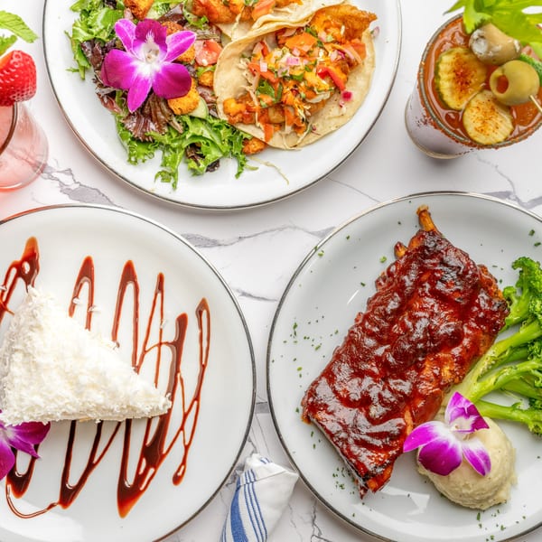 An overhead shot of The Bistro K's Italian dishes, including tacos, ribs, cake, and a Bloody Mary.
